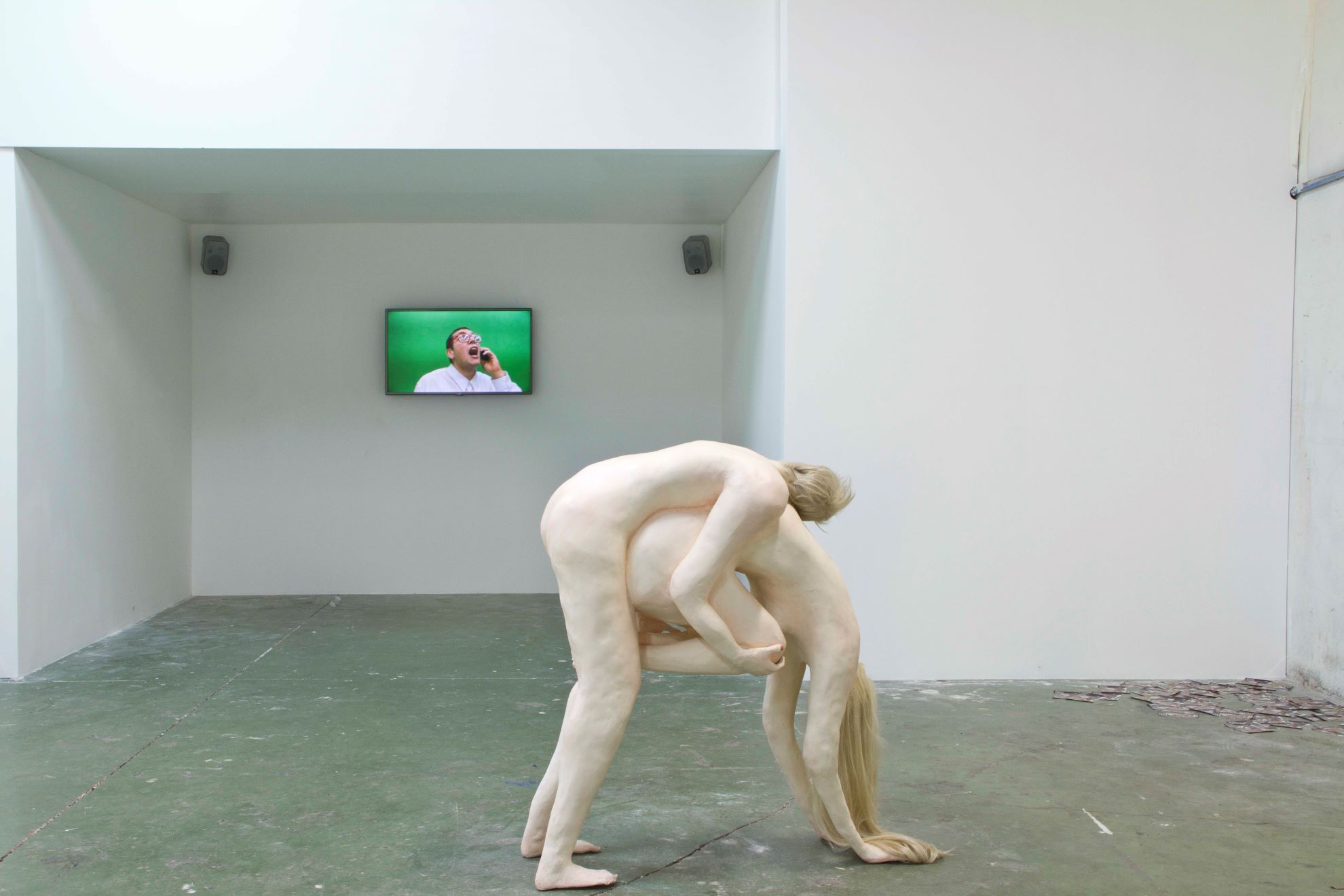 Installation shot of two sculpted figures. One figure is holding the other in a downward position as the other holds them up off the ground.