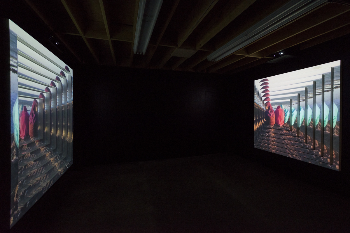 A dark room shows to side-by-side video projections