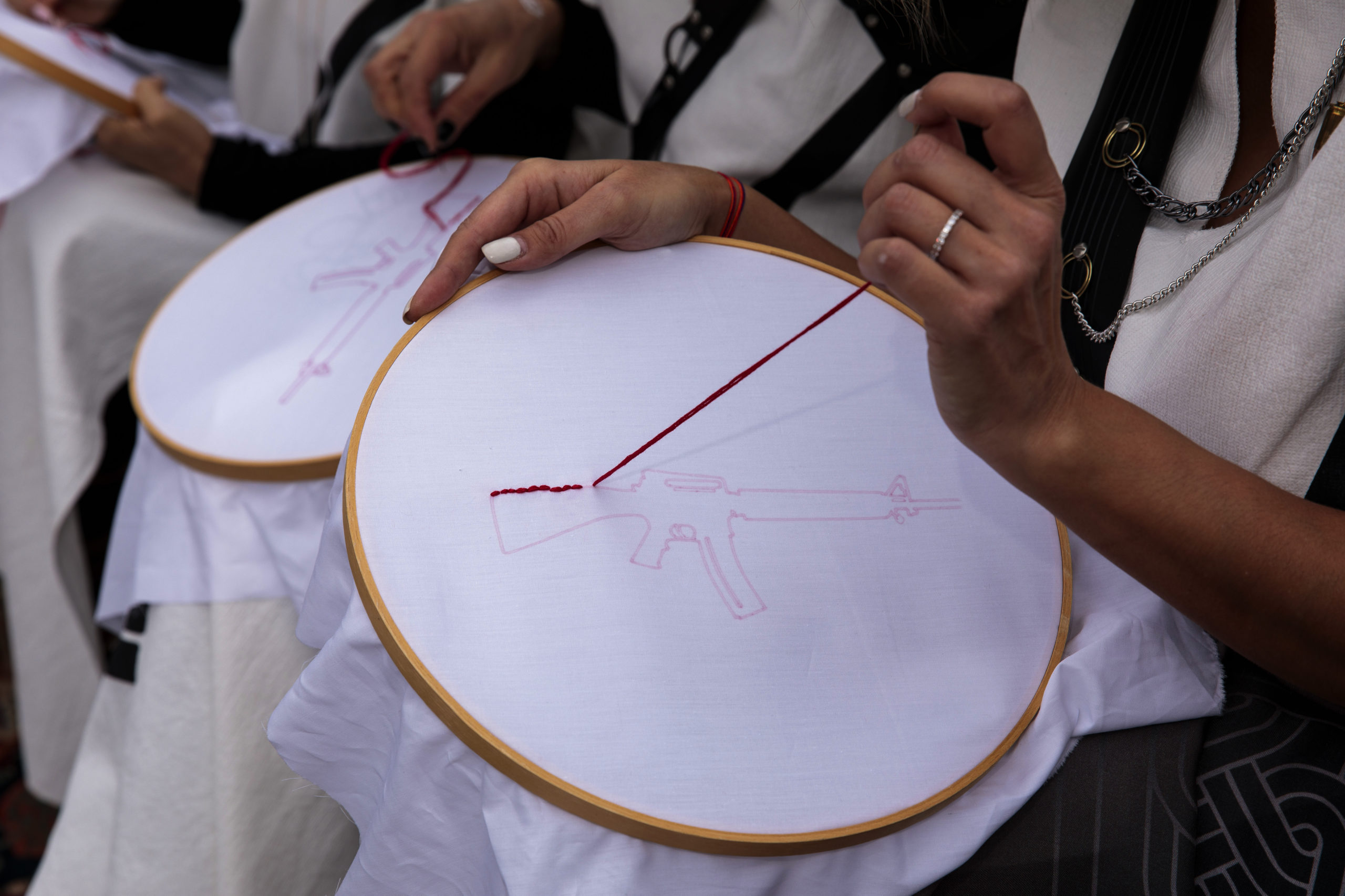 A person's hands doing embroidery of a gun.
