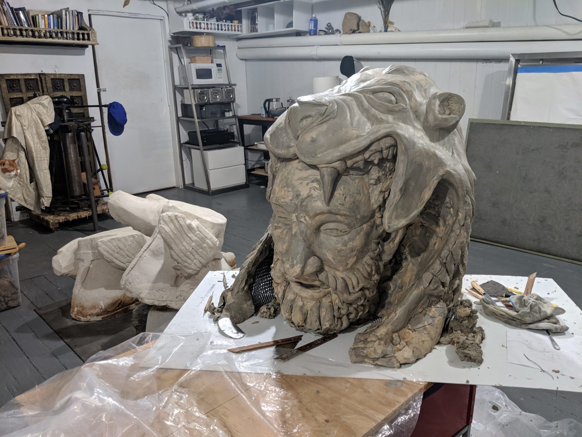 In-progress statue of bearded man with lion skin covering on art studio table
