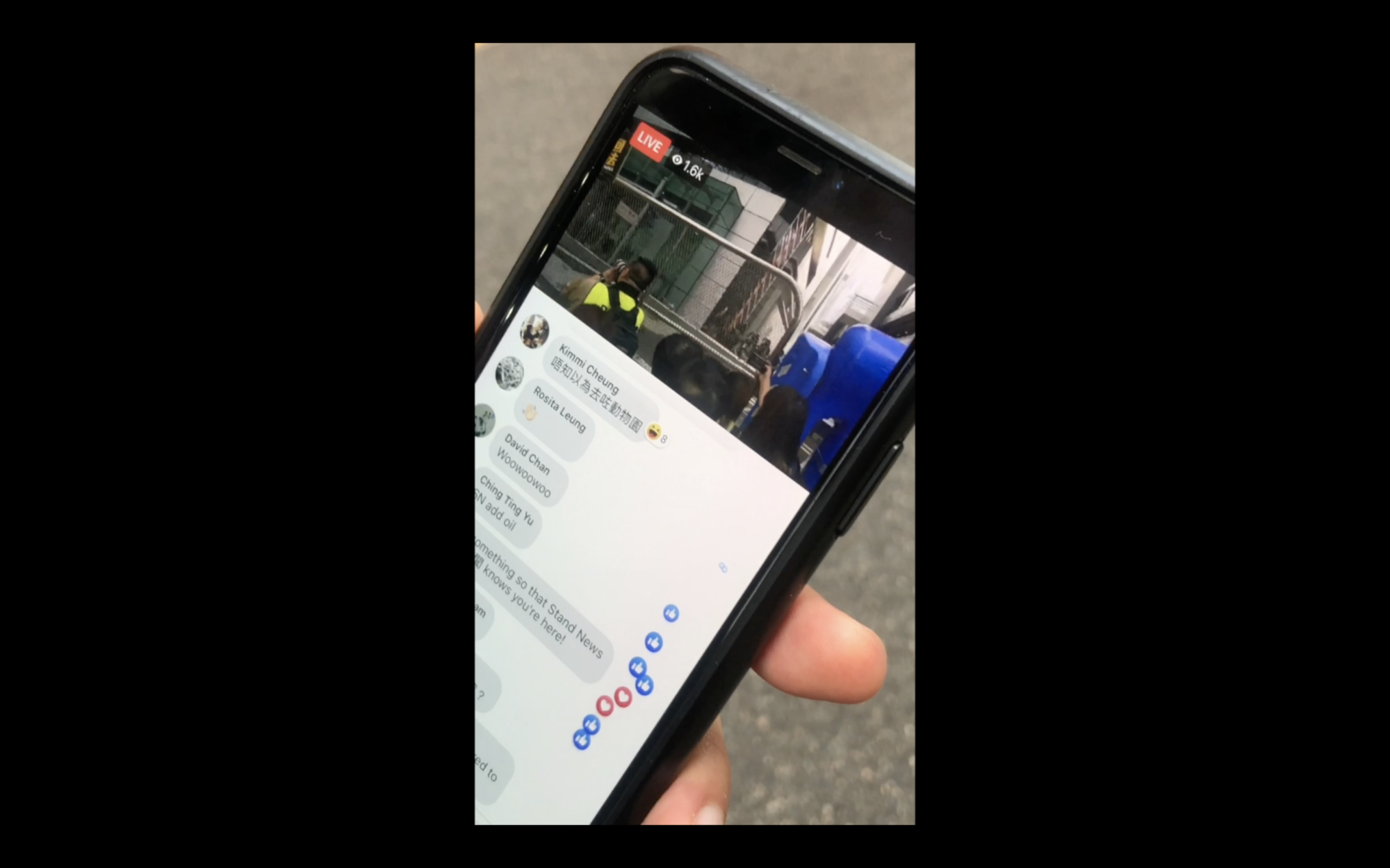 A close up image of a phone showing a Facebook livestream of what appears to be a protest in the street, with 1.6 thousand viewers and many comments which cover what's happening on livestream.