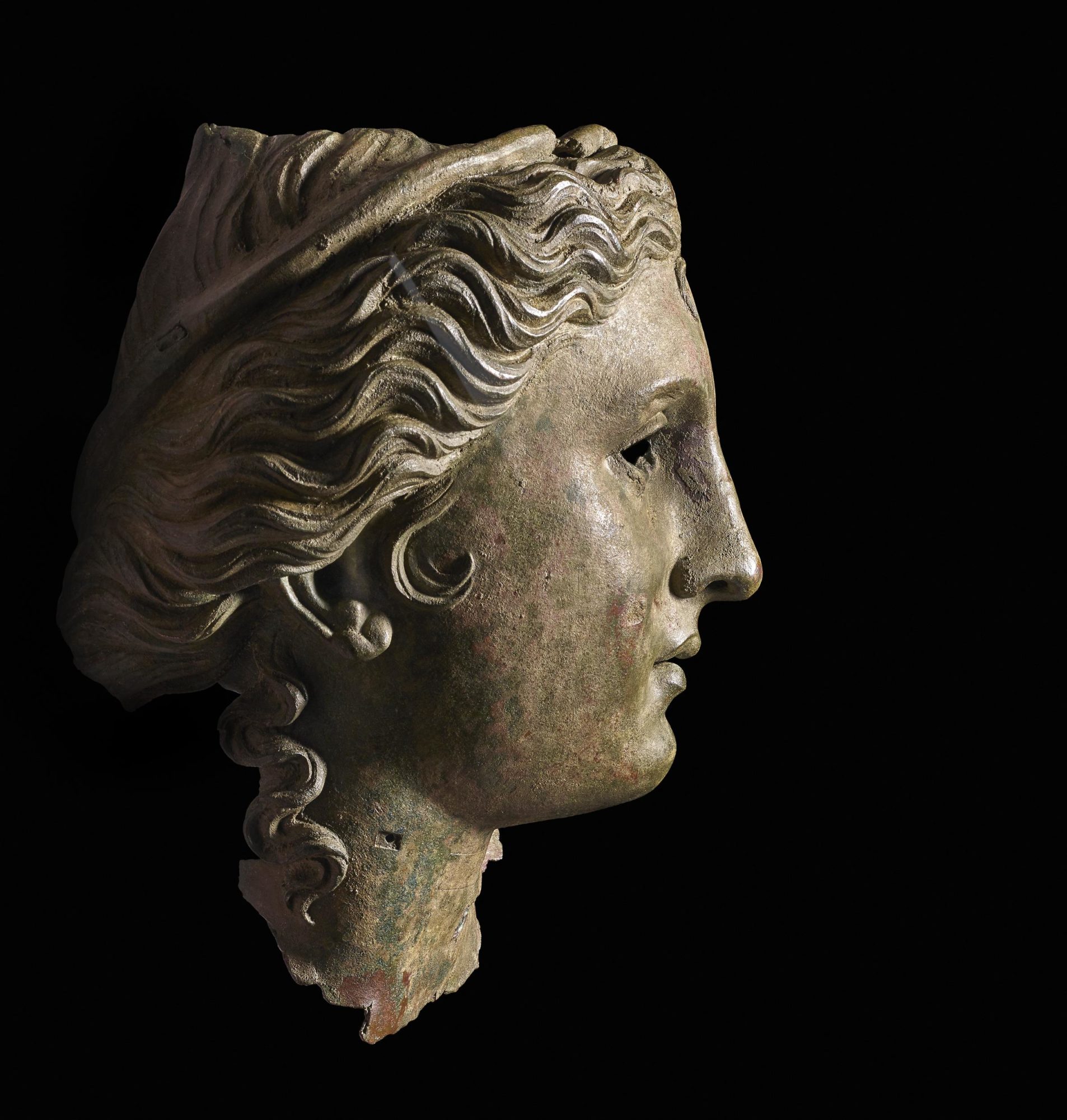 Right side profile of bronze bust of a goddess Anahit. The tops of her hair and headband visible, as well as her right ear.