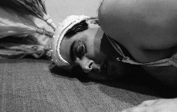 Leppe dons a decorative headpiece as he lies with his head pushed against the floor.