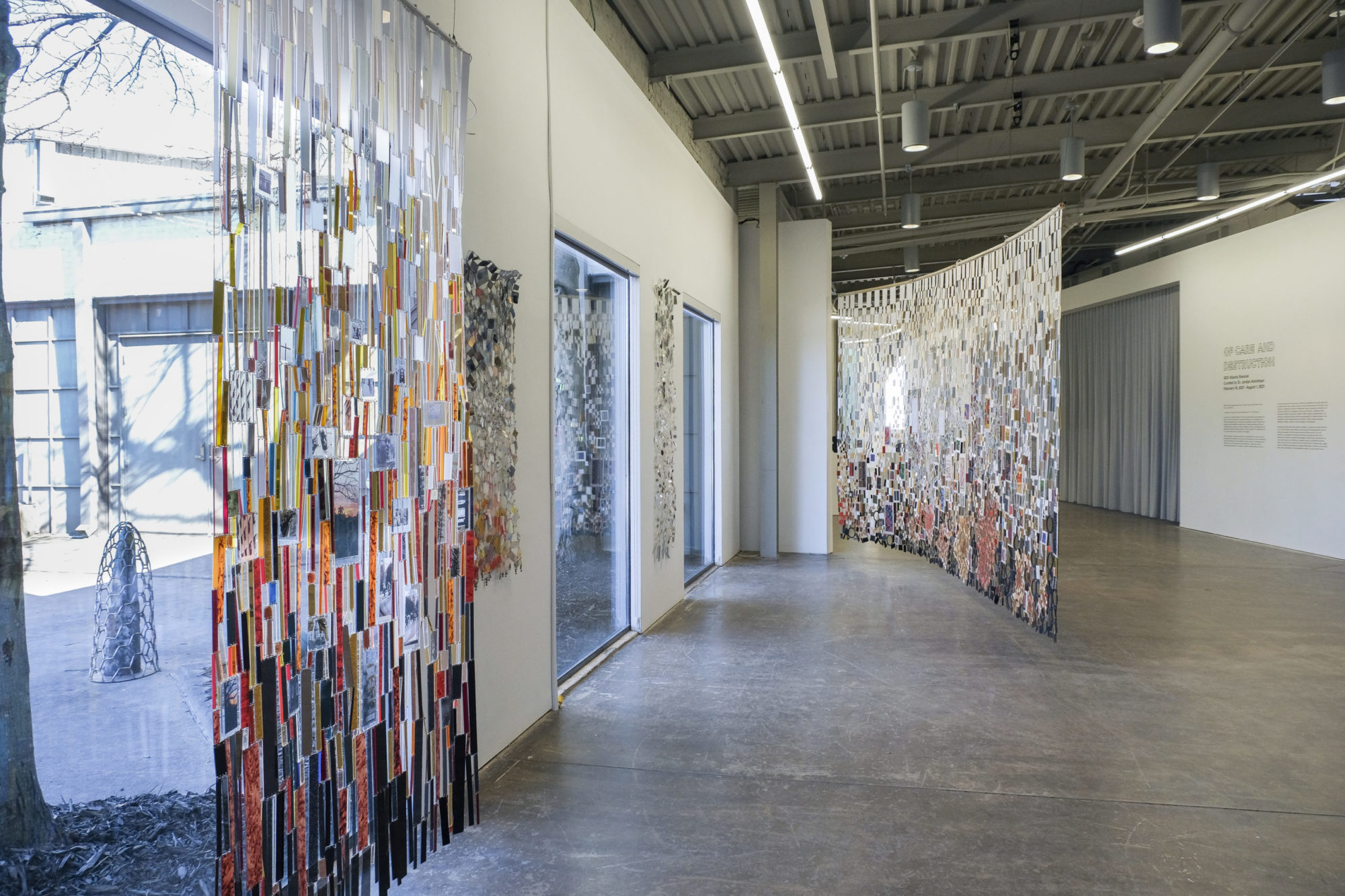 Colorful mixed-media assemblage is displayed vertically in an installation.