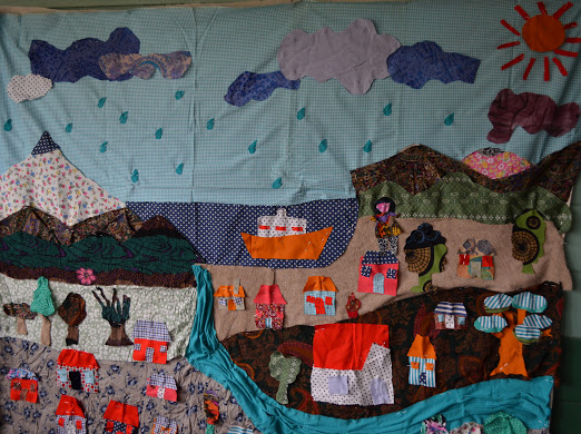 A colorful textile, depicting an intricate landscape, hangs from the wall.