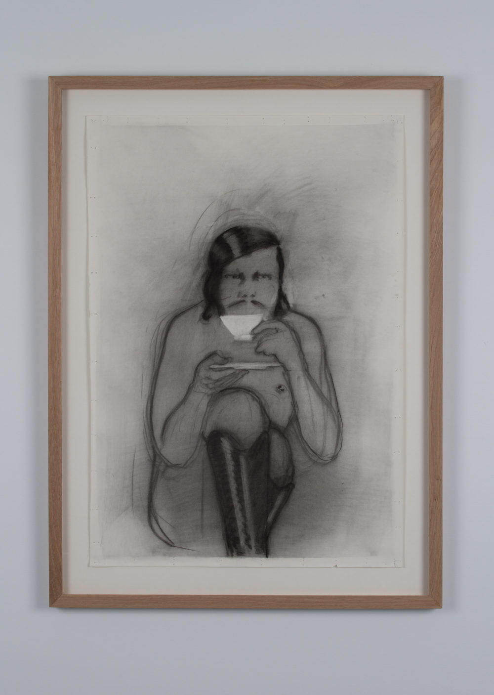 A charcoal drawing of a person sitting shirtless and crosslegged holding a tea cup and saucer in front of their face. They are wearing tall black boots and have a mustache.