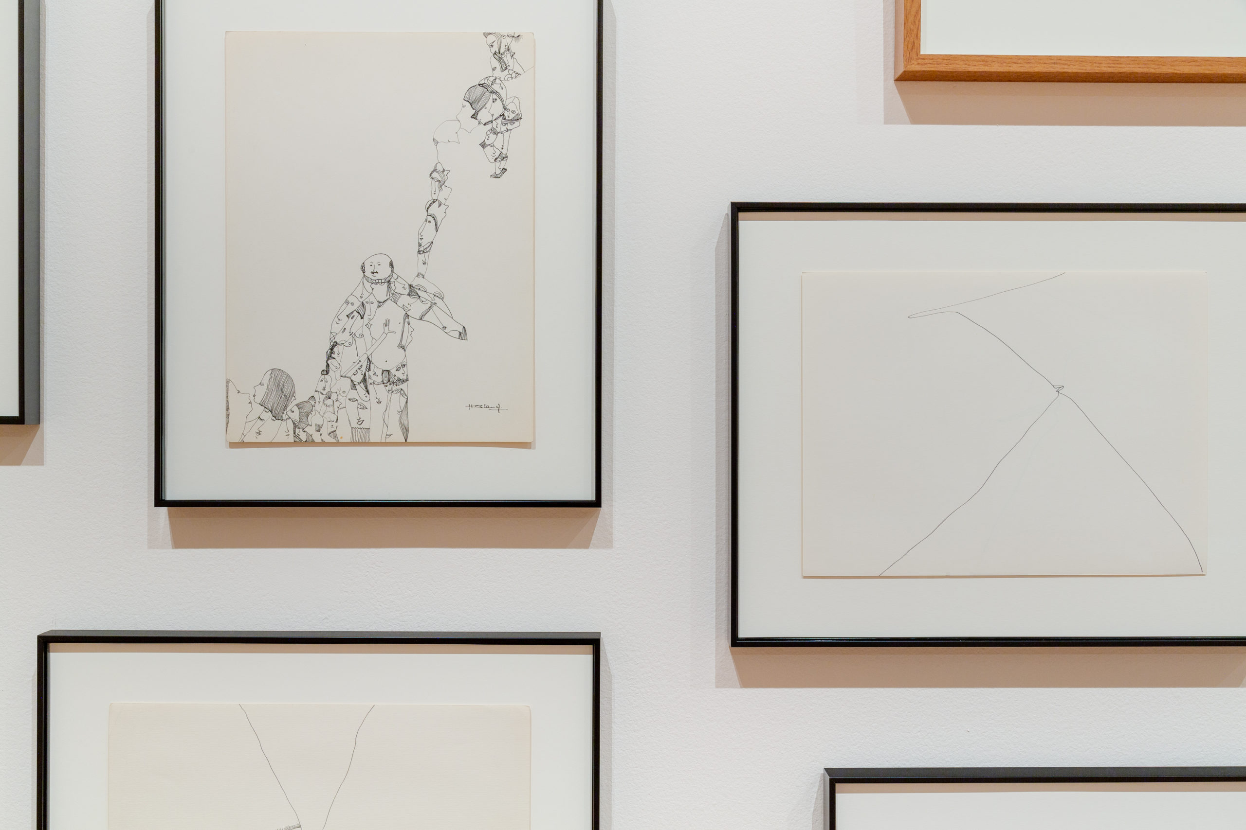Art work is presented on white gallery walls in thin black frames.