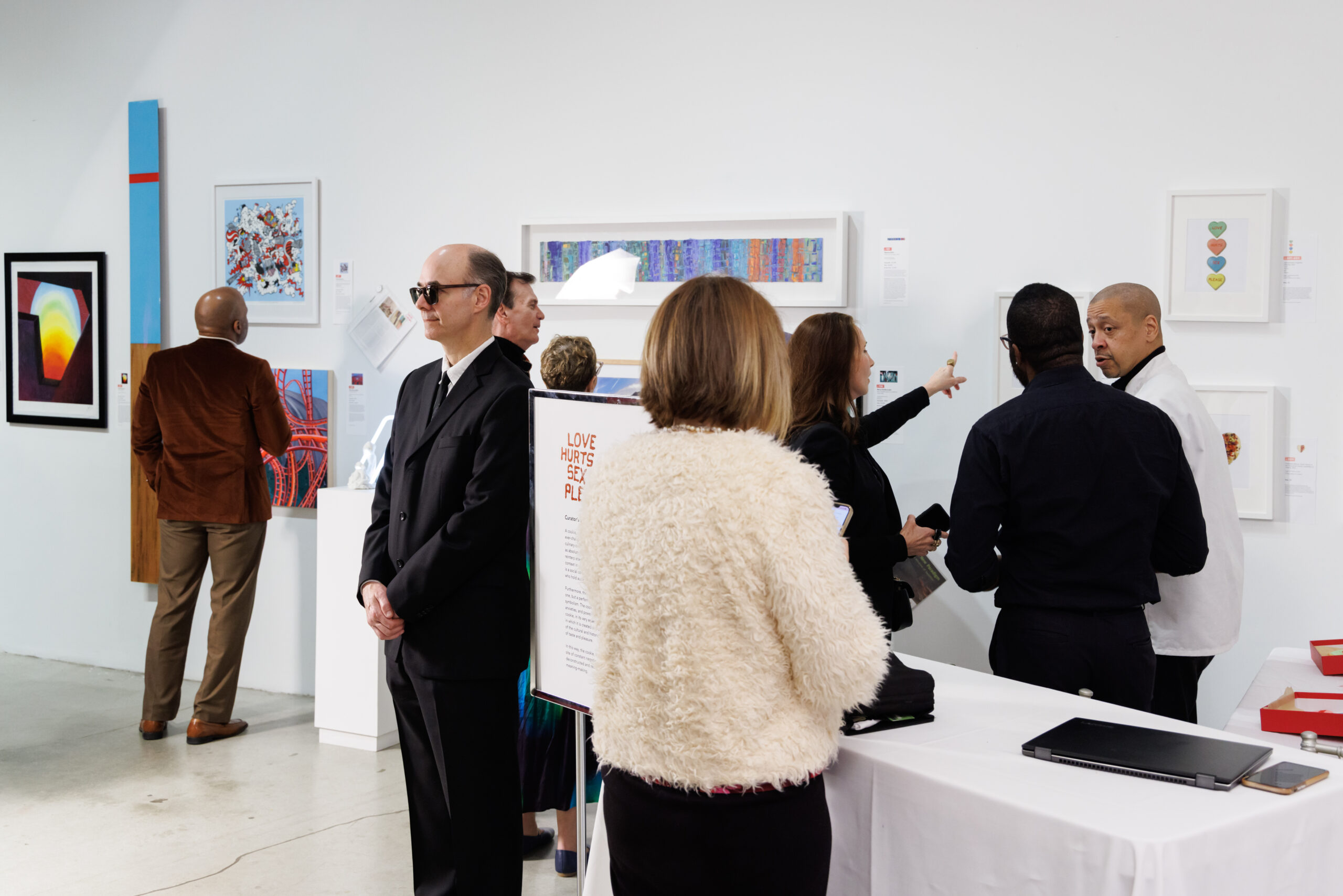 Image of a group of people gathering next to a wall of artwork.