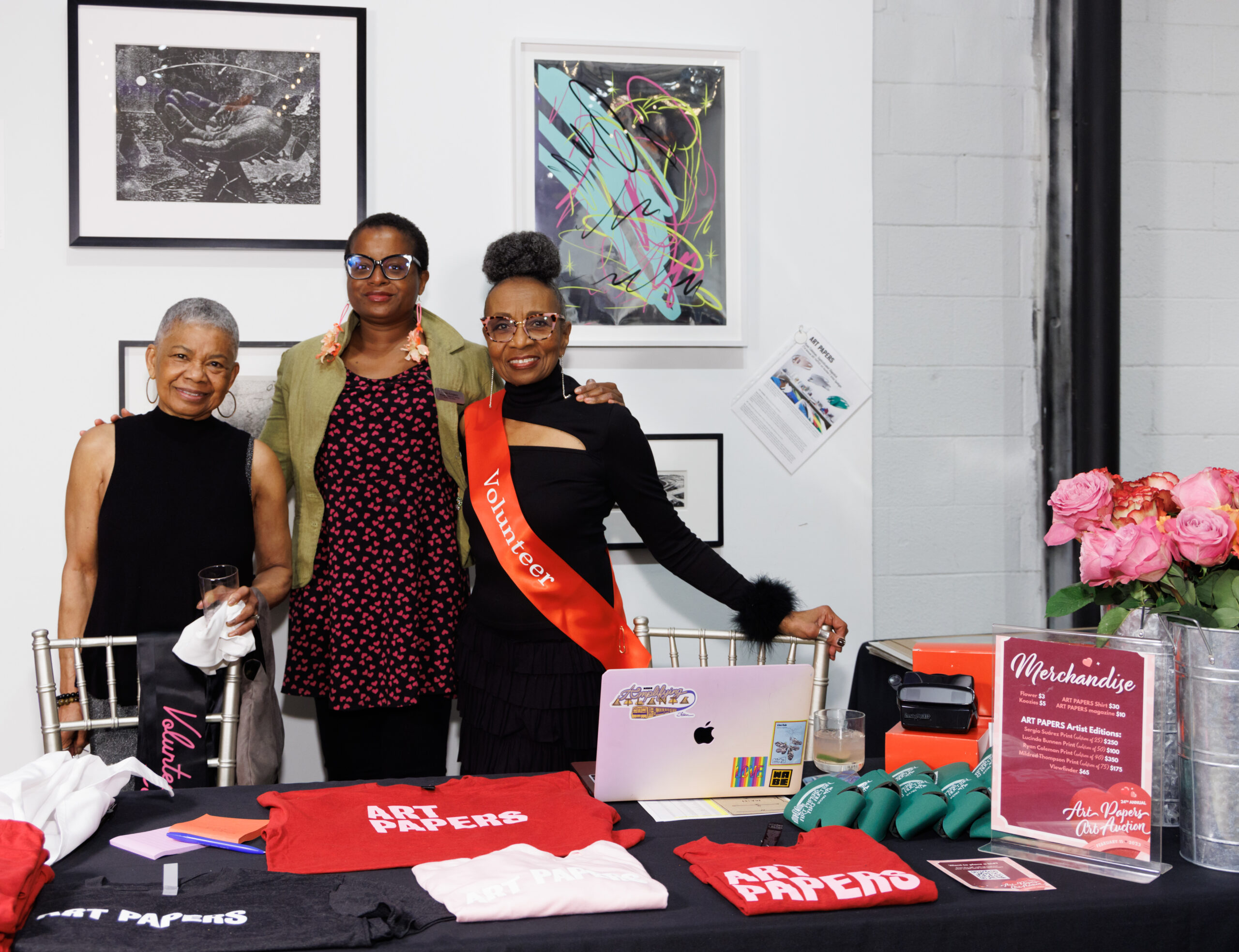 Image of three women posing behind a black table with Art Papers merchandise.