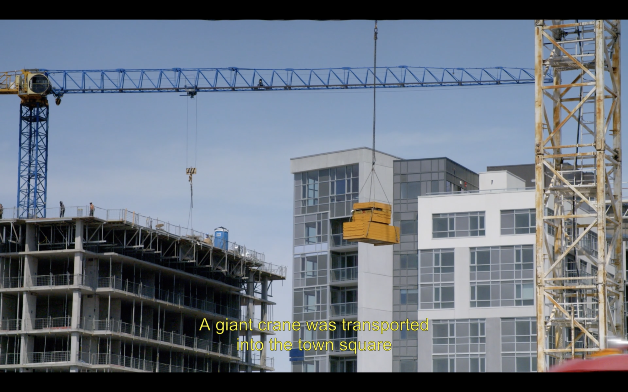 Still of crane at a construction site, subtitled 