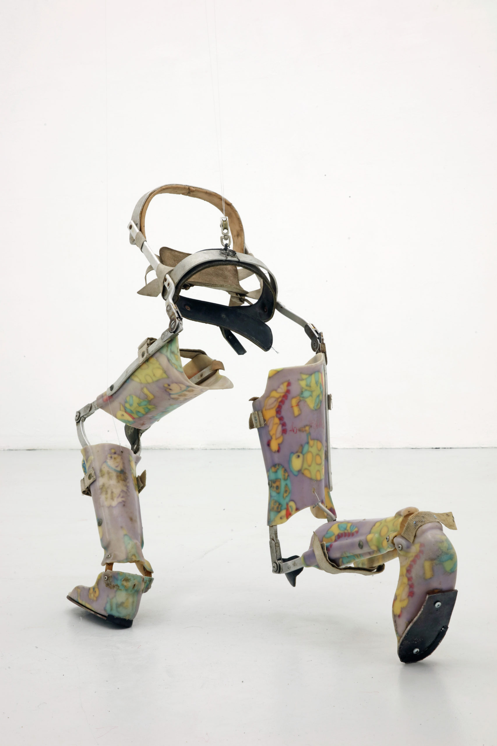 a half bodied figure made out of prosthetics is placed in a running position against white gallery walls.