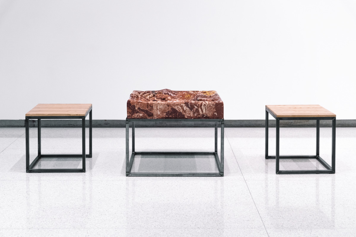 This is an installation detail that features a red and brown marbled slab of material that resembles a small table or stool.