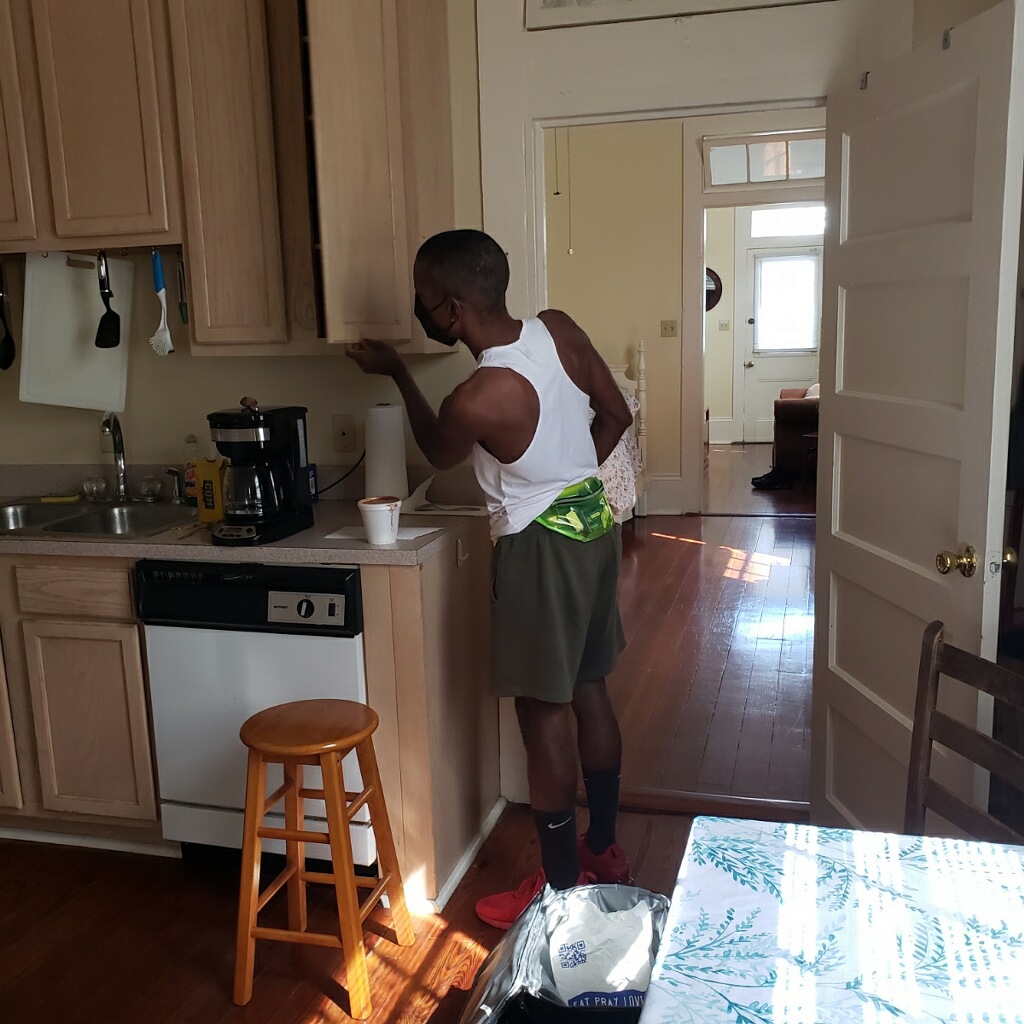 This is a photograph of artist Malcolm Peacock opening a cabinet in a kitchen for the performance of We Served...