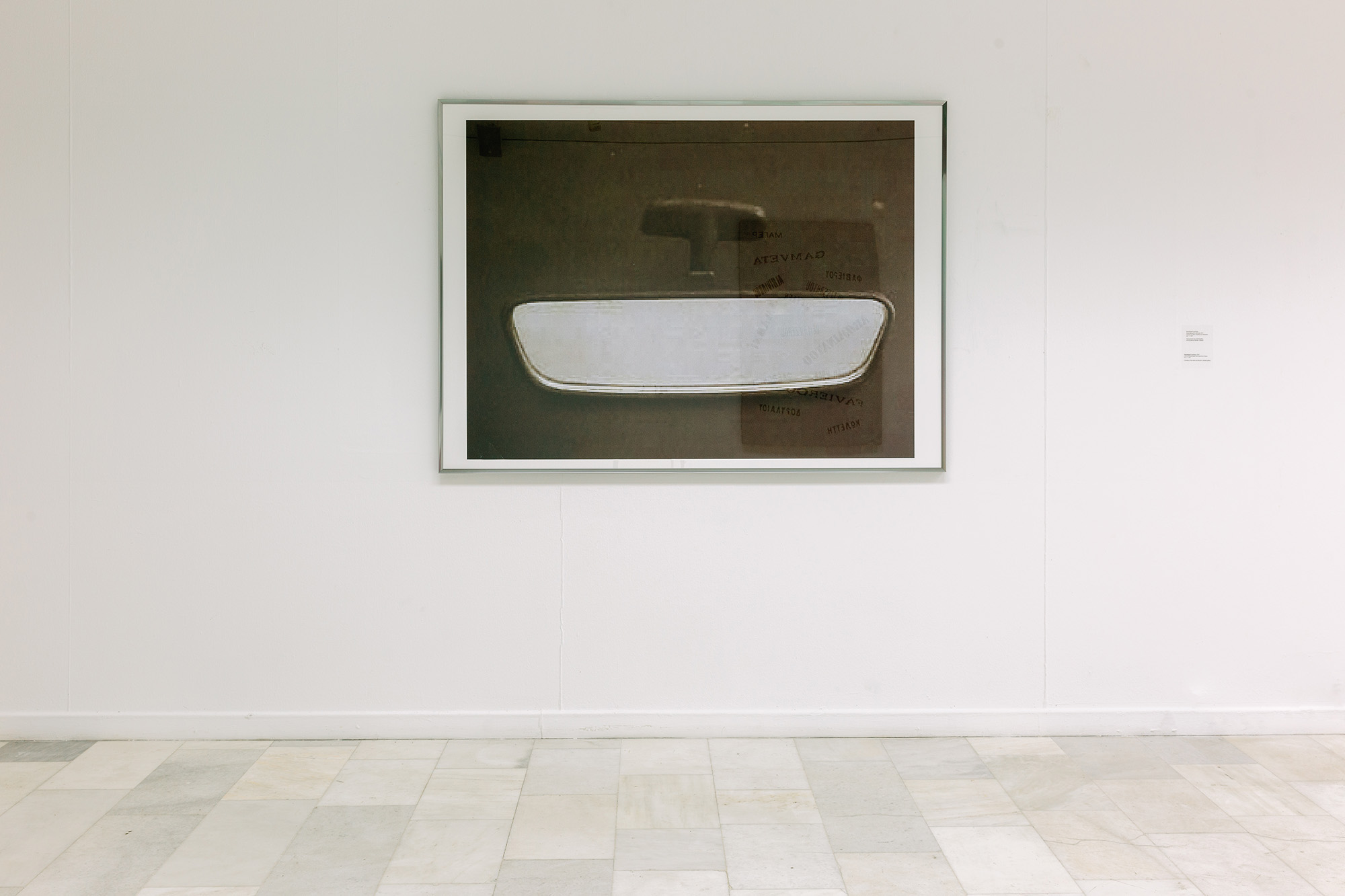 The piece, Developed in Privacy by the artist Rallou Panagiotou featuring the photgraph of a rearview car mirror.