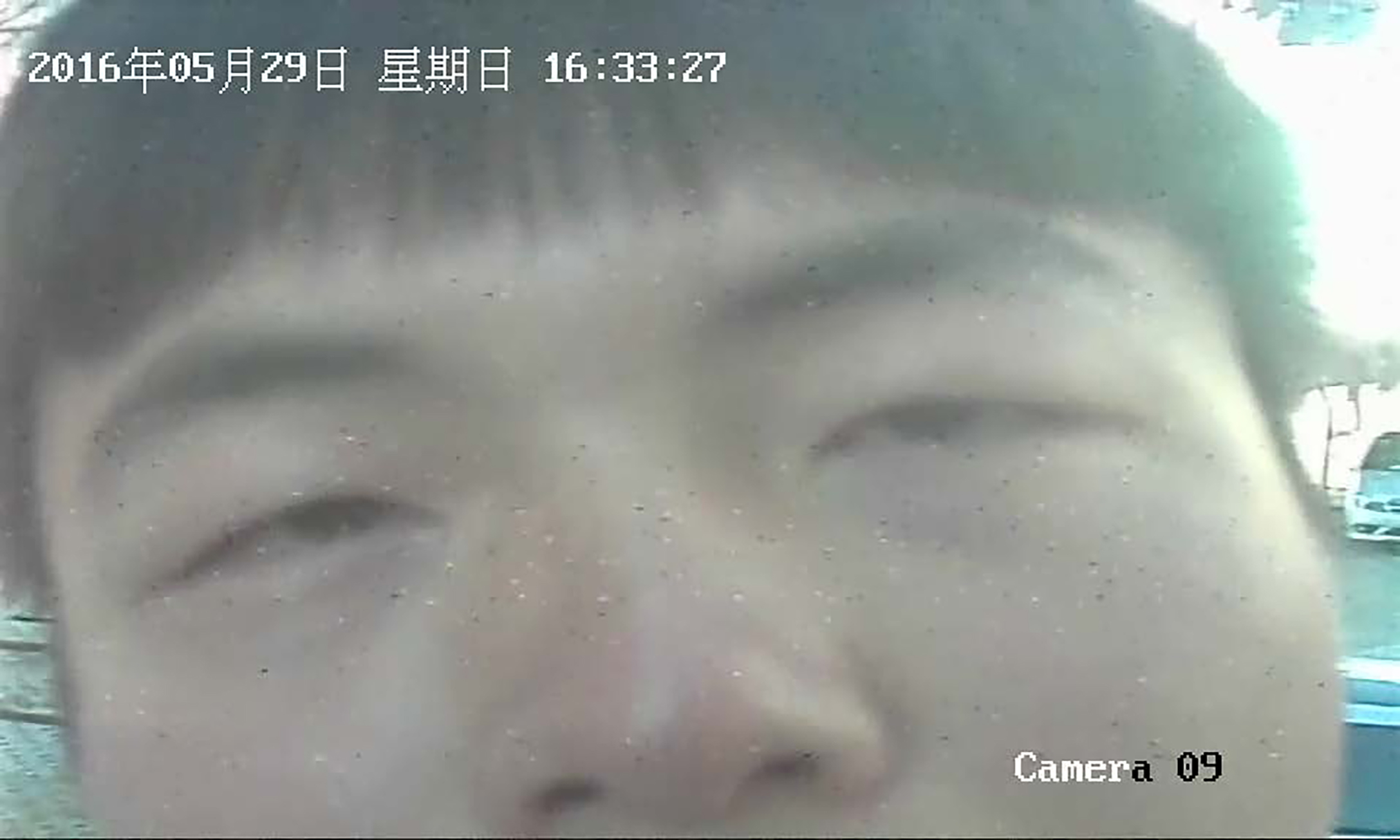 Artist, Ge Yulu stares directly into a surveillance camera, the shot is from the point of view of the security camera