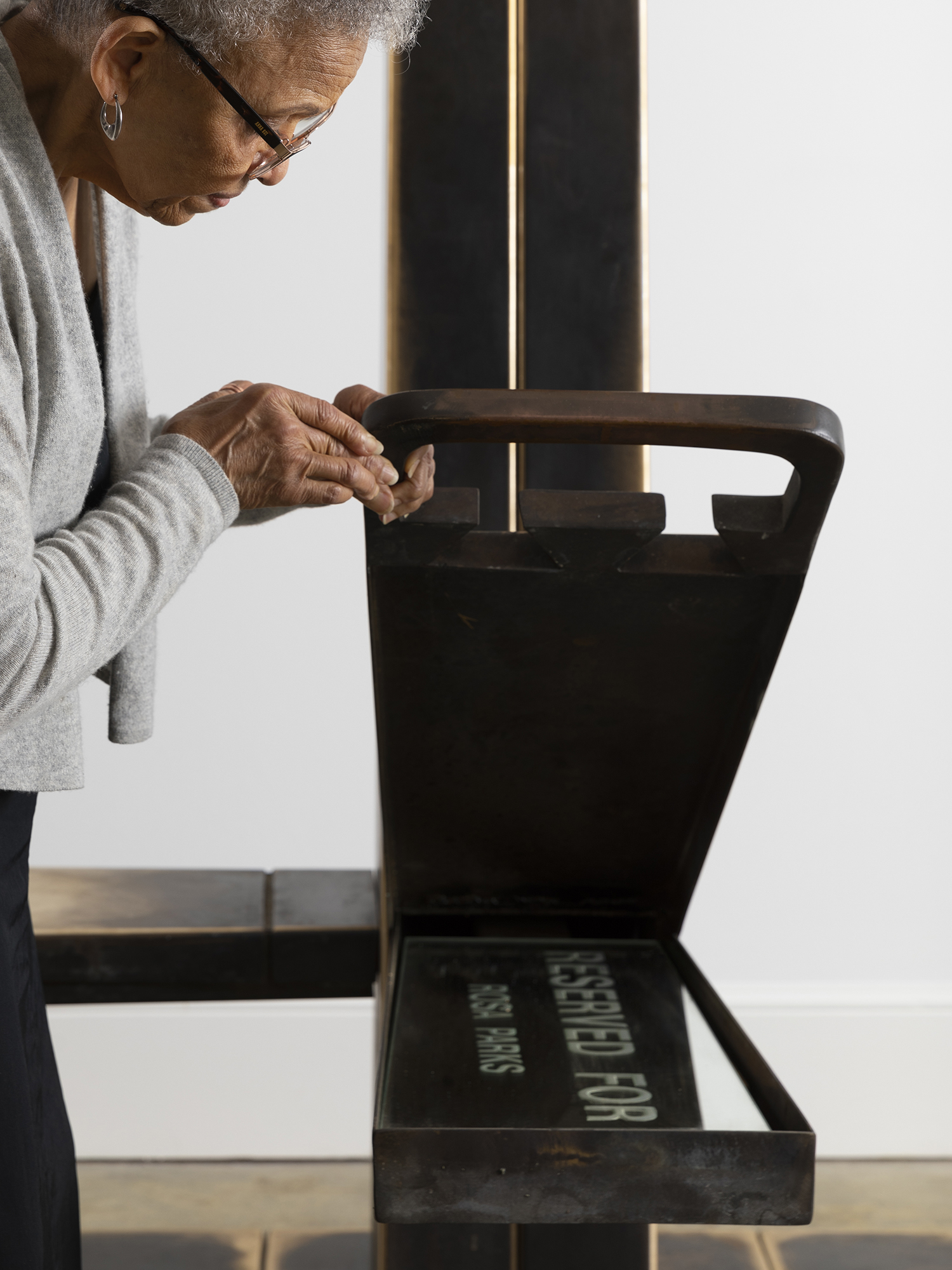 A person lifts up a part of the Montgomery Bus Stop sculpture revealing a mirror inscribed with 