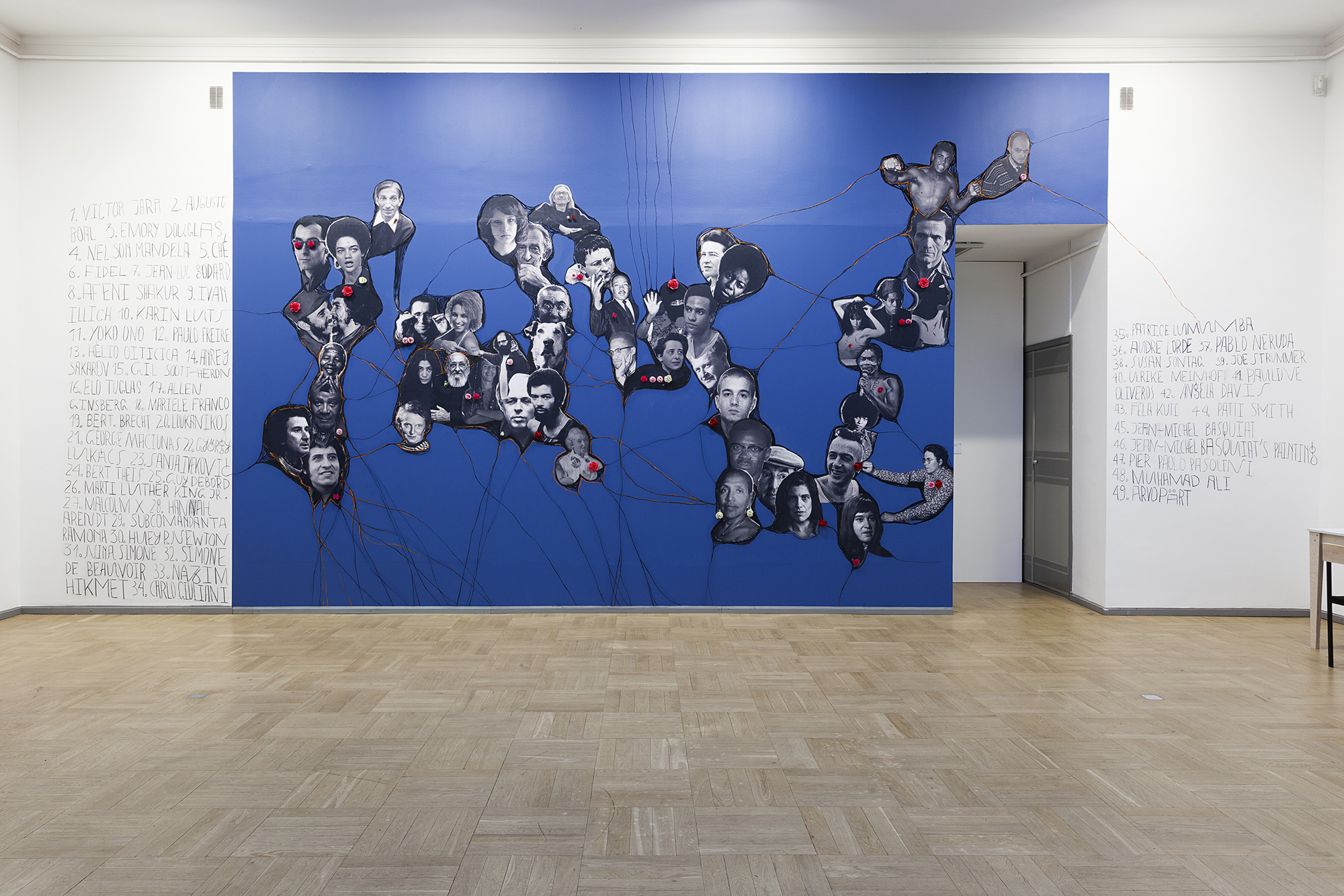 A bright blue mural featuring portraits of historical figures