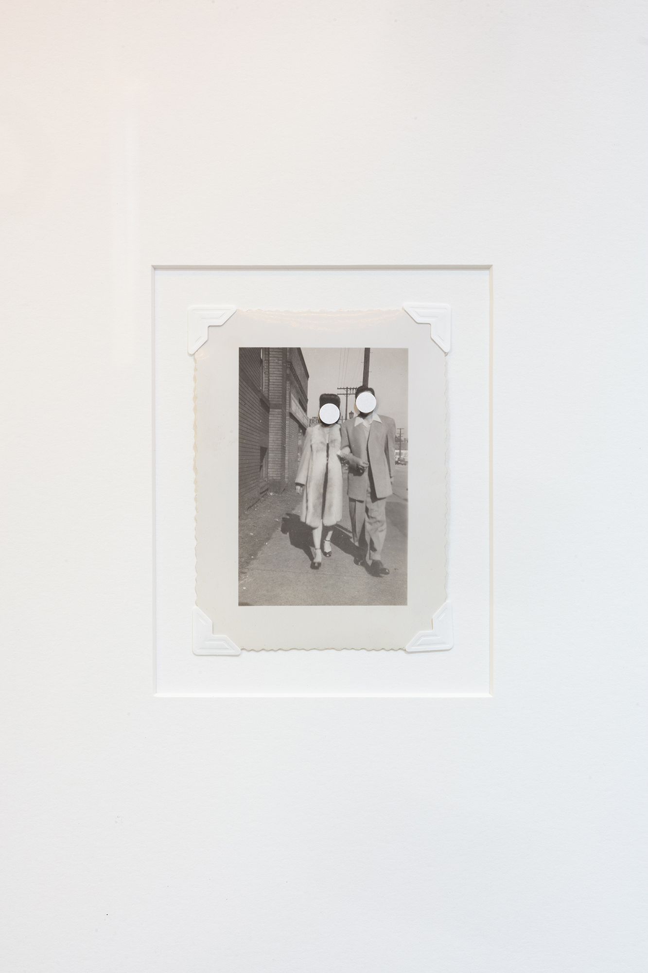 A black and white archival photograph of a couple walking down the street