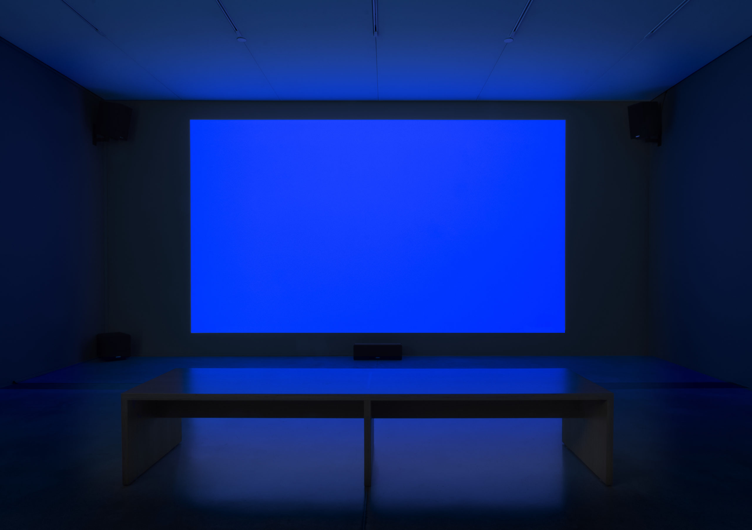 A dark room with a vibrant blue panel that reflects onto the ground.