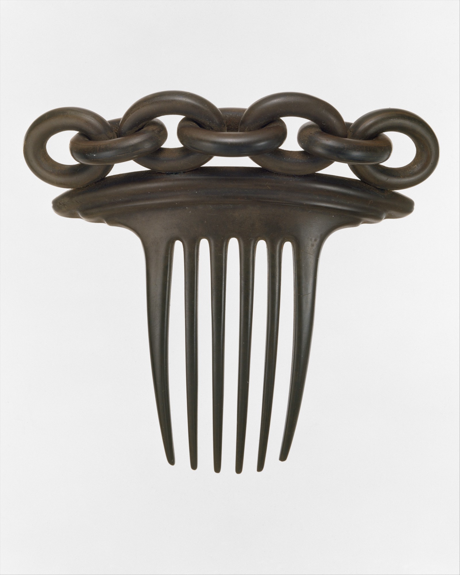 A comb with a chainlink handle, made of vulcanite, a dark brown substance.