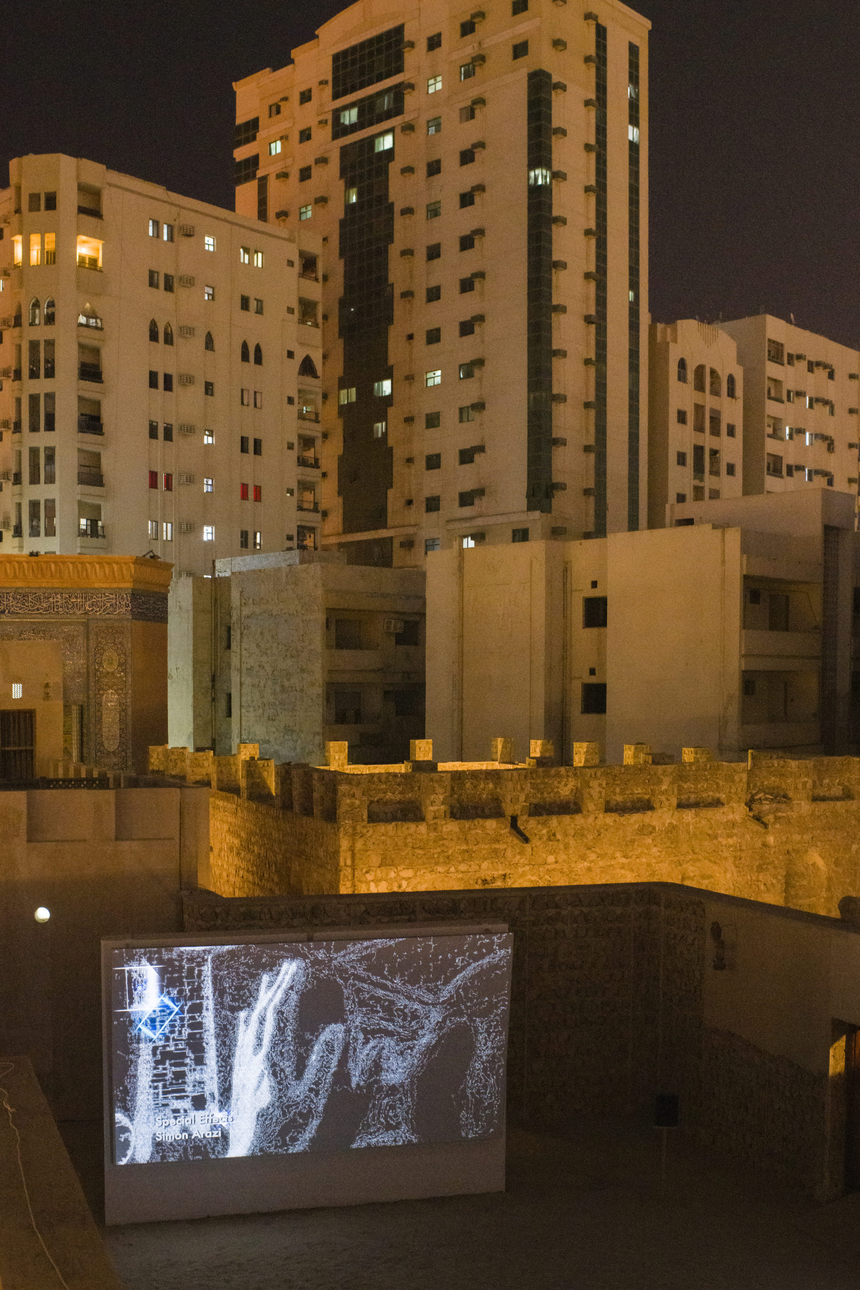 Amid a white and tan city scape made of concrete and stone, a screen depicting a pixelated hand sits in the bottom left corner of the image.