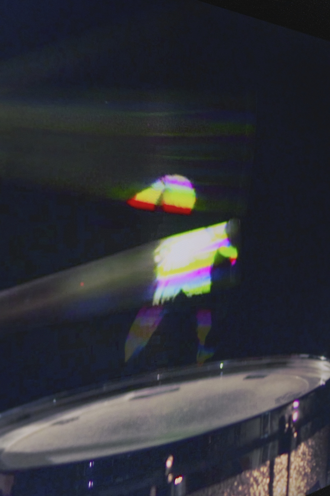 A hologram of varying color captures a figure mid-motion through the movement of drumsticks.