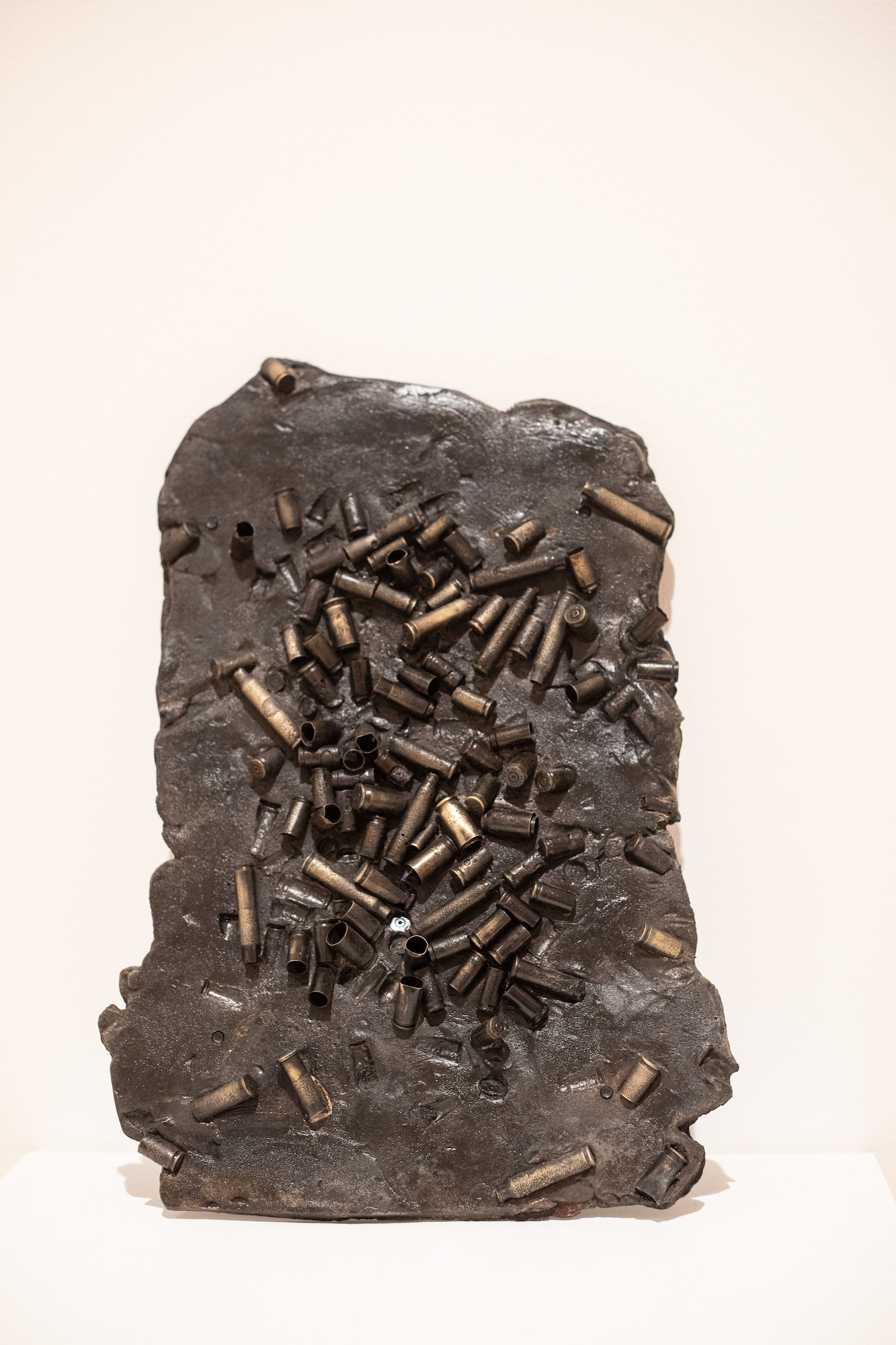 A dark mass of cast iron with bullet shells imbedded in it.