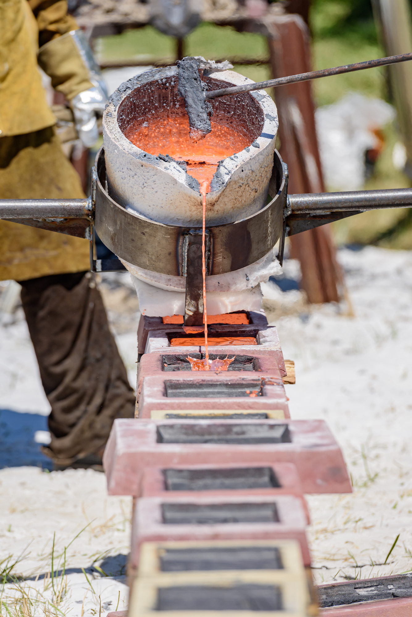 Molten iron is being poured down a line of molds