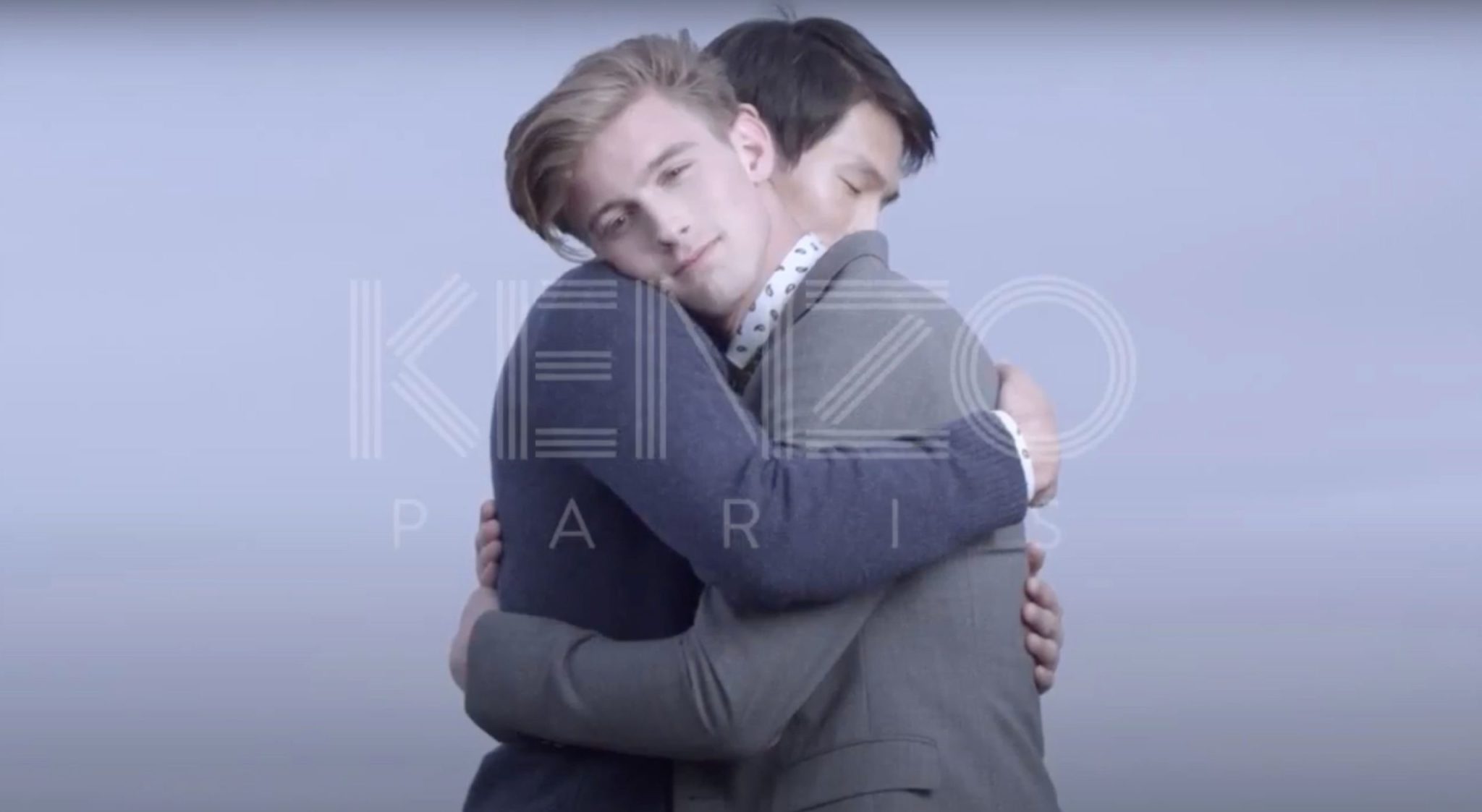Two men embrace on a set with a large watermark that read 