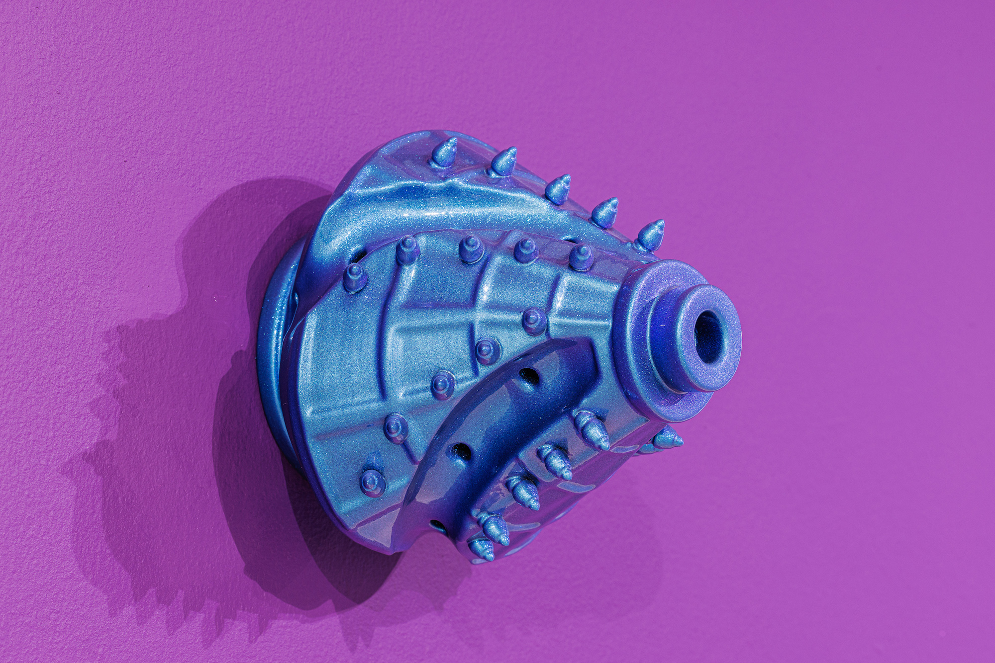 A purple wall with a funky blue drill bit shines opalescently.