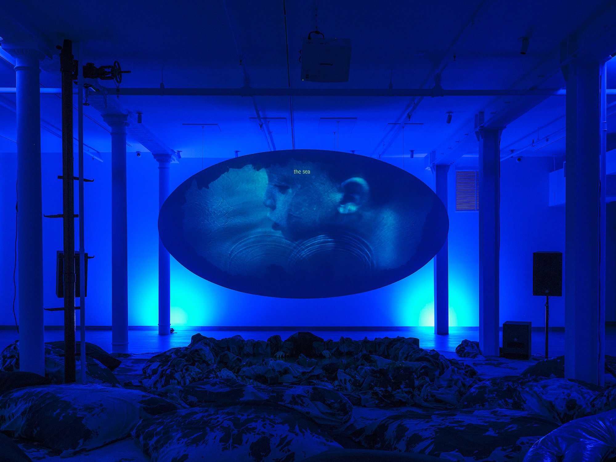 A blue room with an oval screen playing a video
