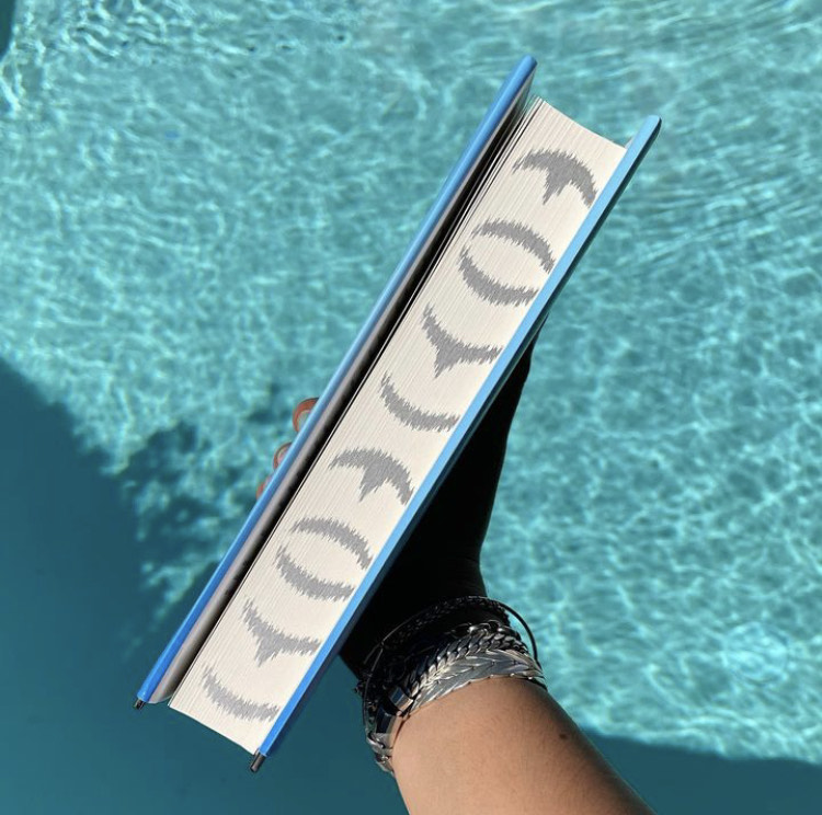 Person holding a blue book over water