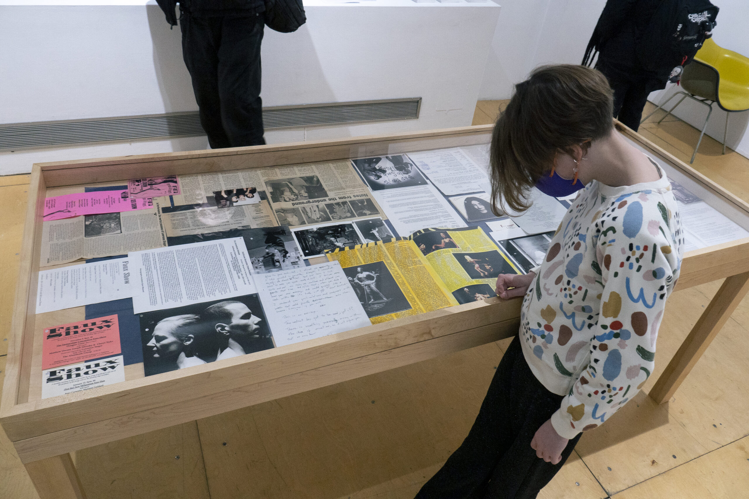 Person looks down into display case full of pages, filled with text