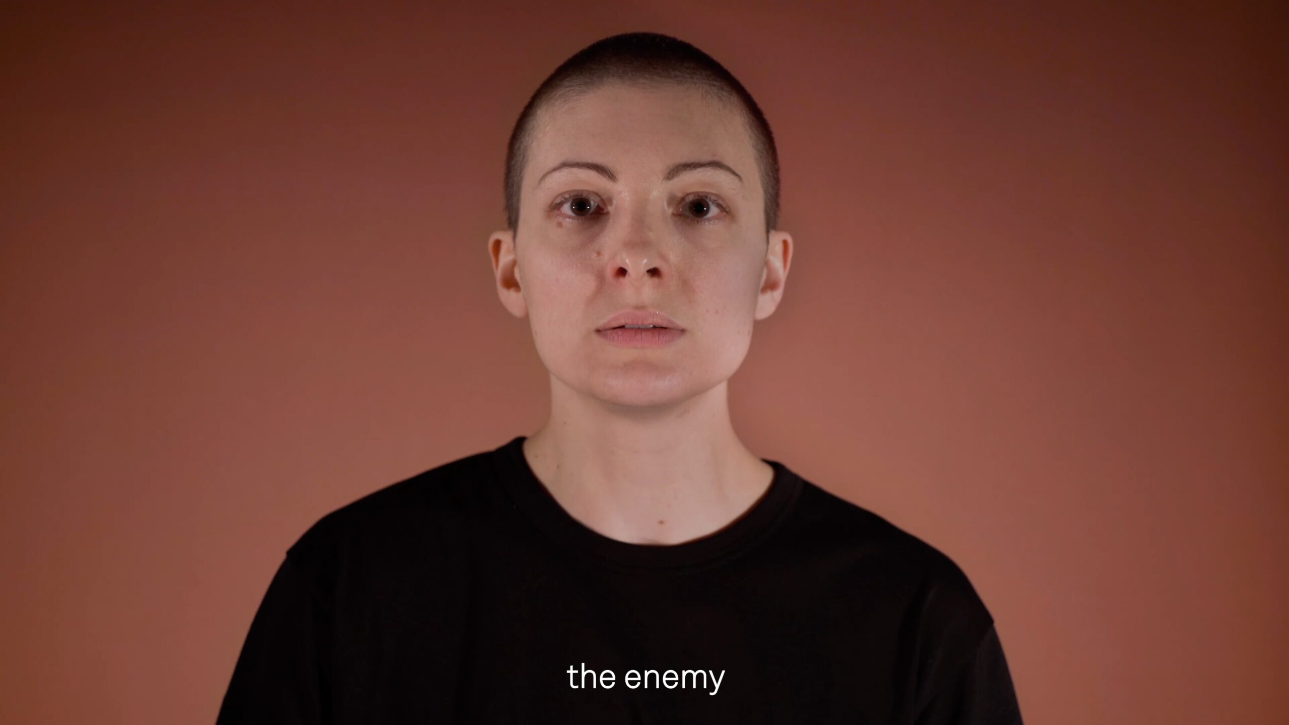 Video still of a person with a shaved head