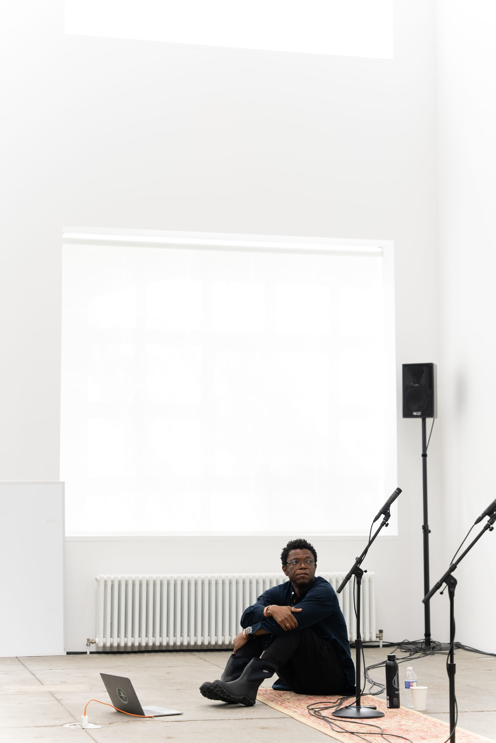 Image of the artist sitting on the floor during rehearsal