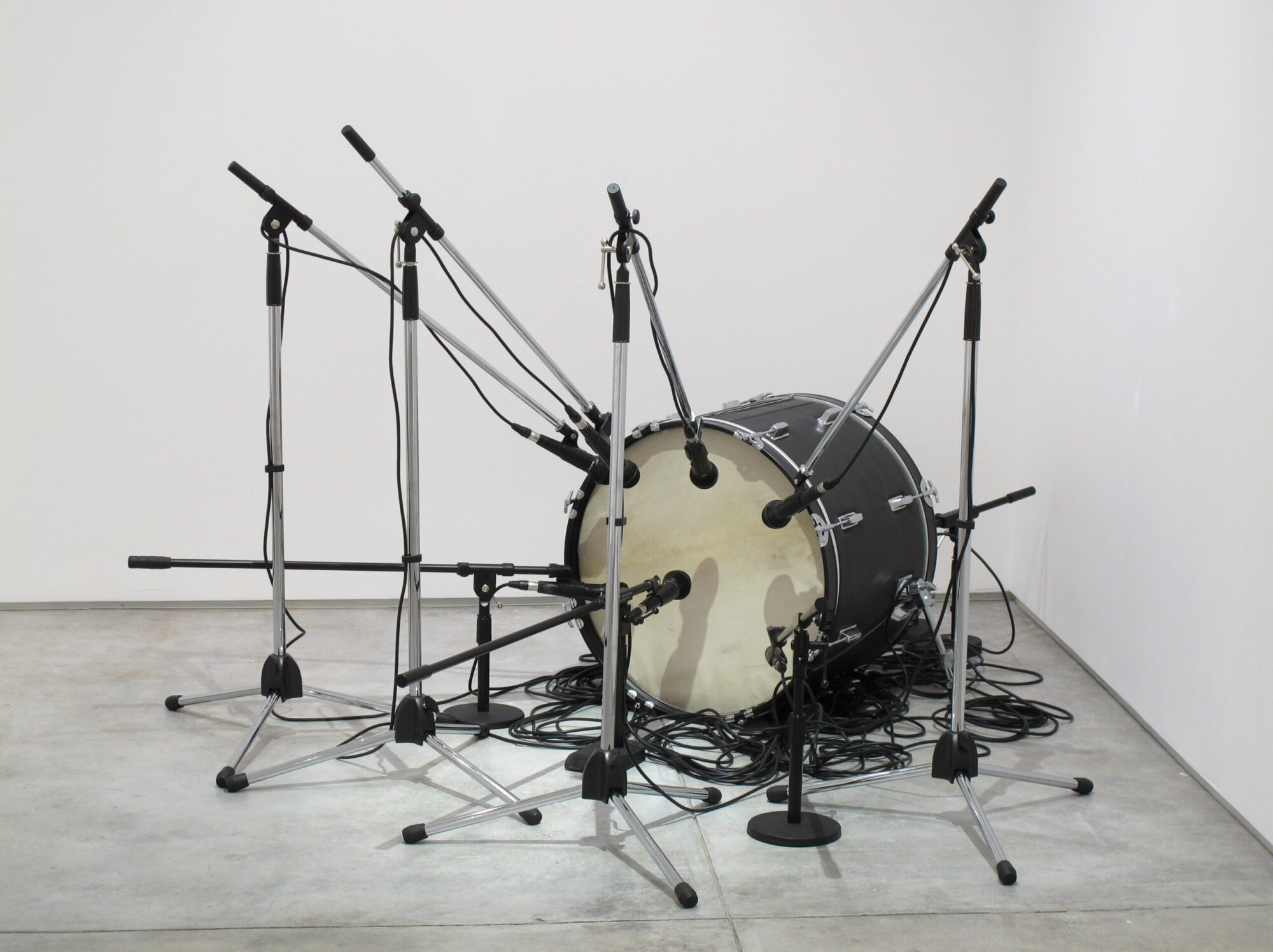 A drum with microphones attached to various stands pointing towards the drum.