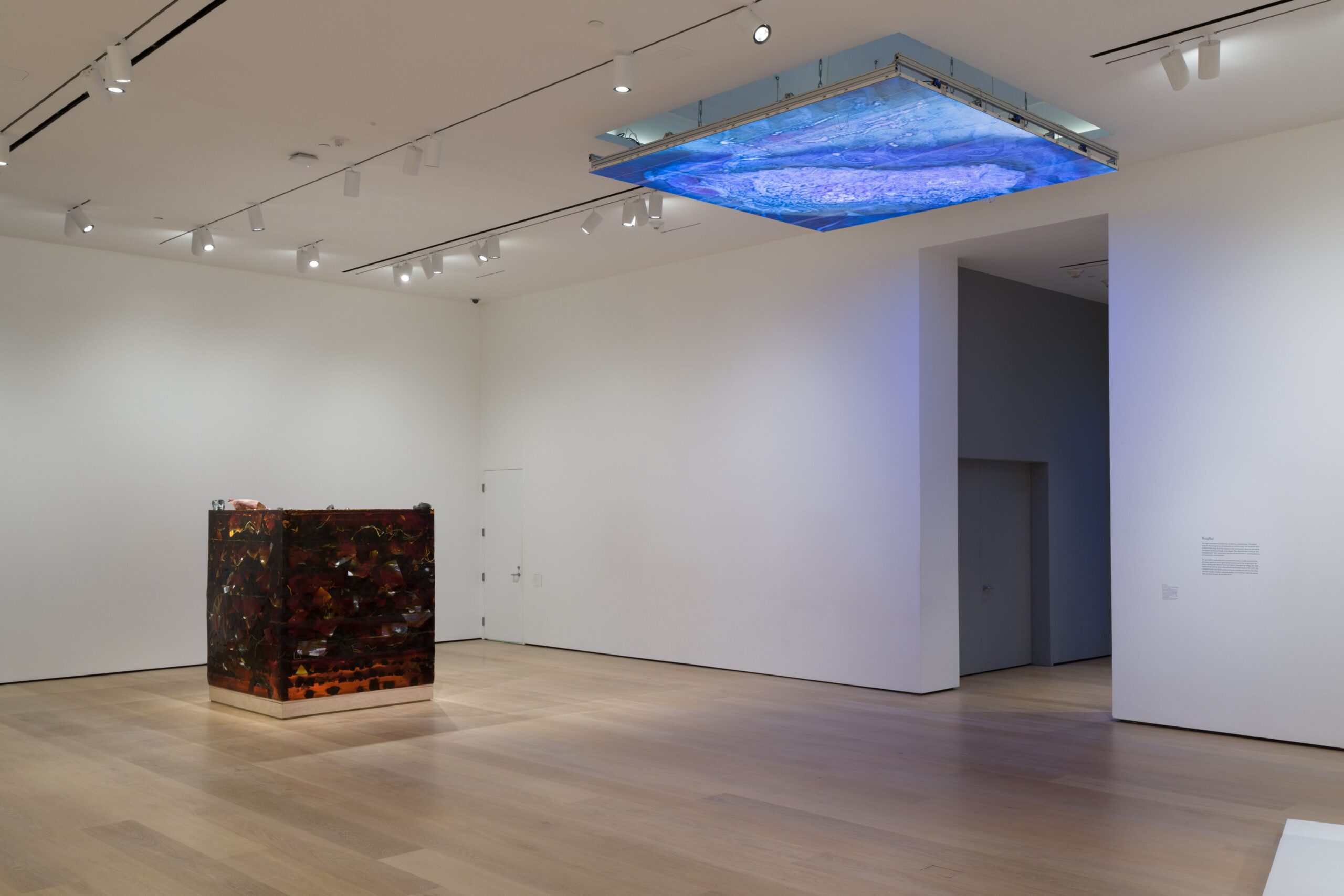 Image of a white room with a dark block off to the left and a blue geologic screen affixed to the ceiling.