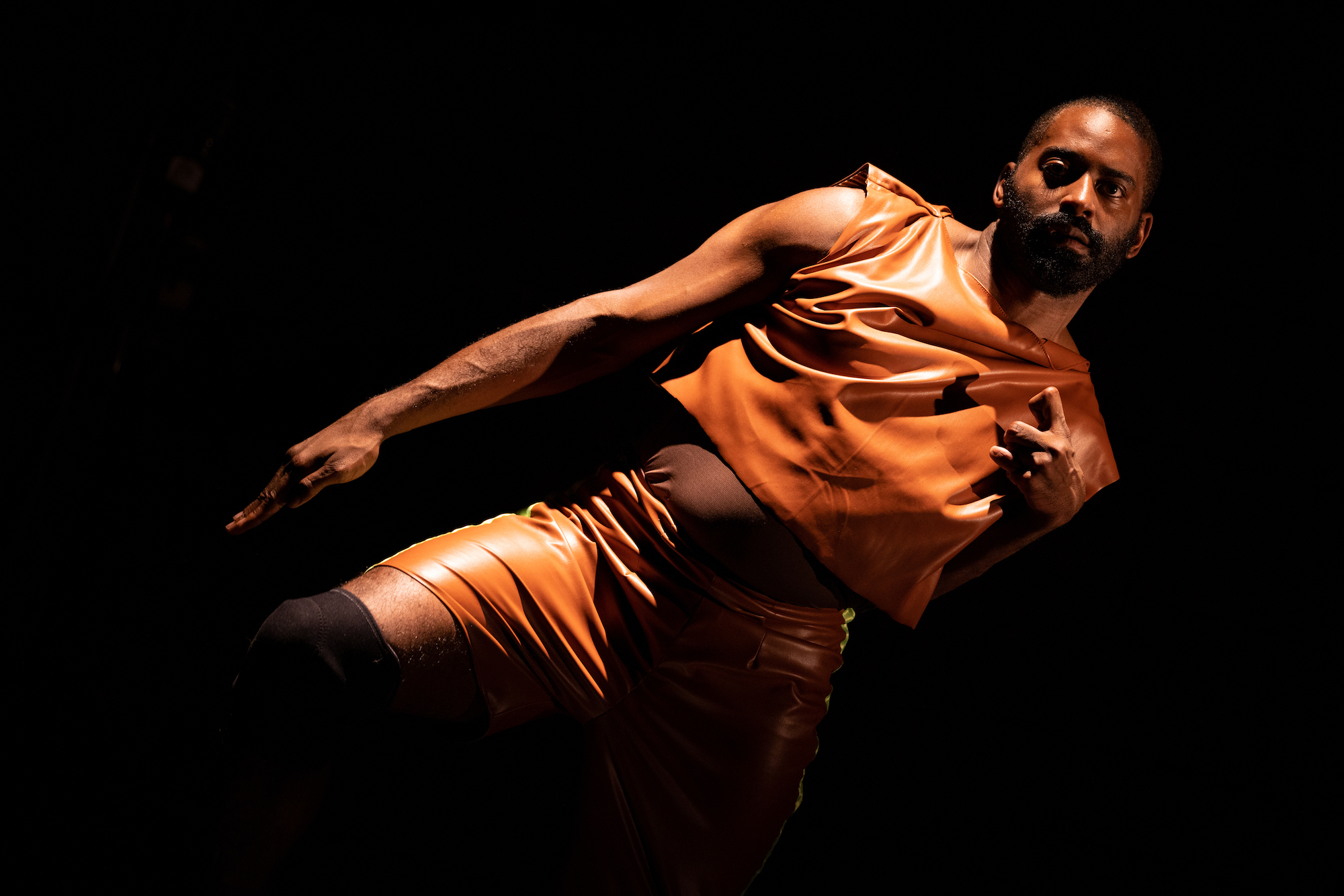 A black man captured mid-performance against dark background