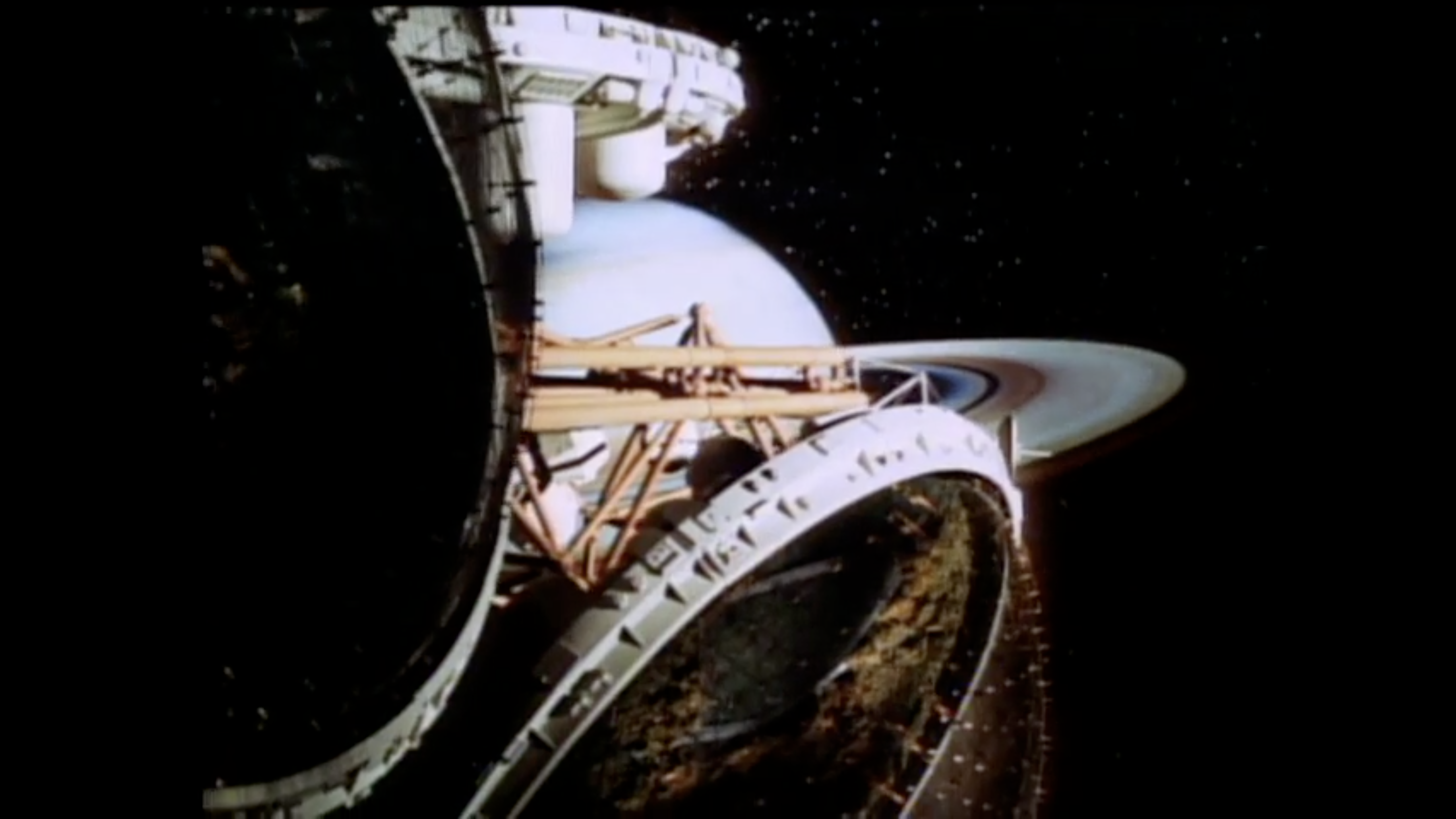 A screenshot of a video of a multi-domed space structure floating in front of a planet.