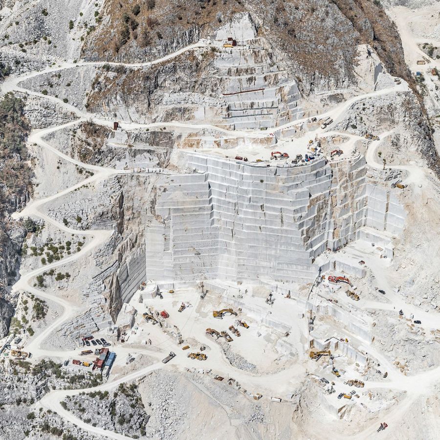 A plain, white construction site with many construction vehicles on different parts of the site.