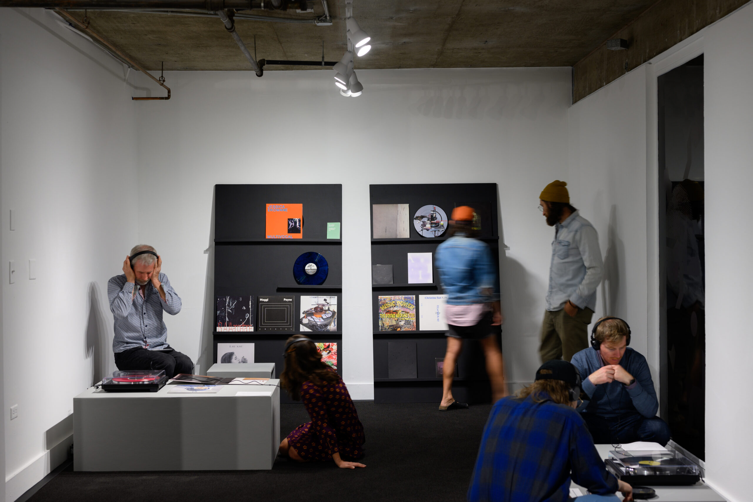 People interact with an audio installation where they can listen to vinyl albums with headphones.