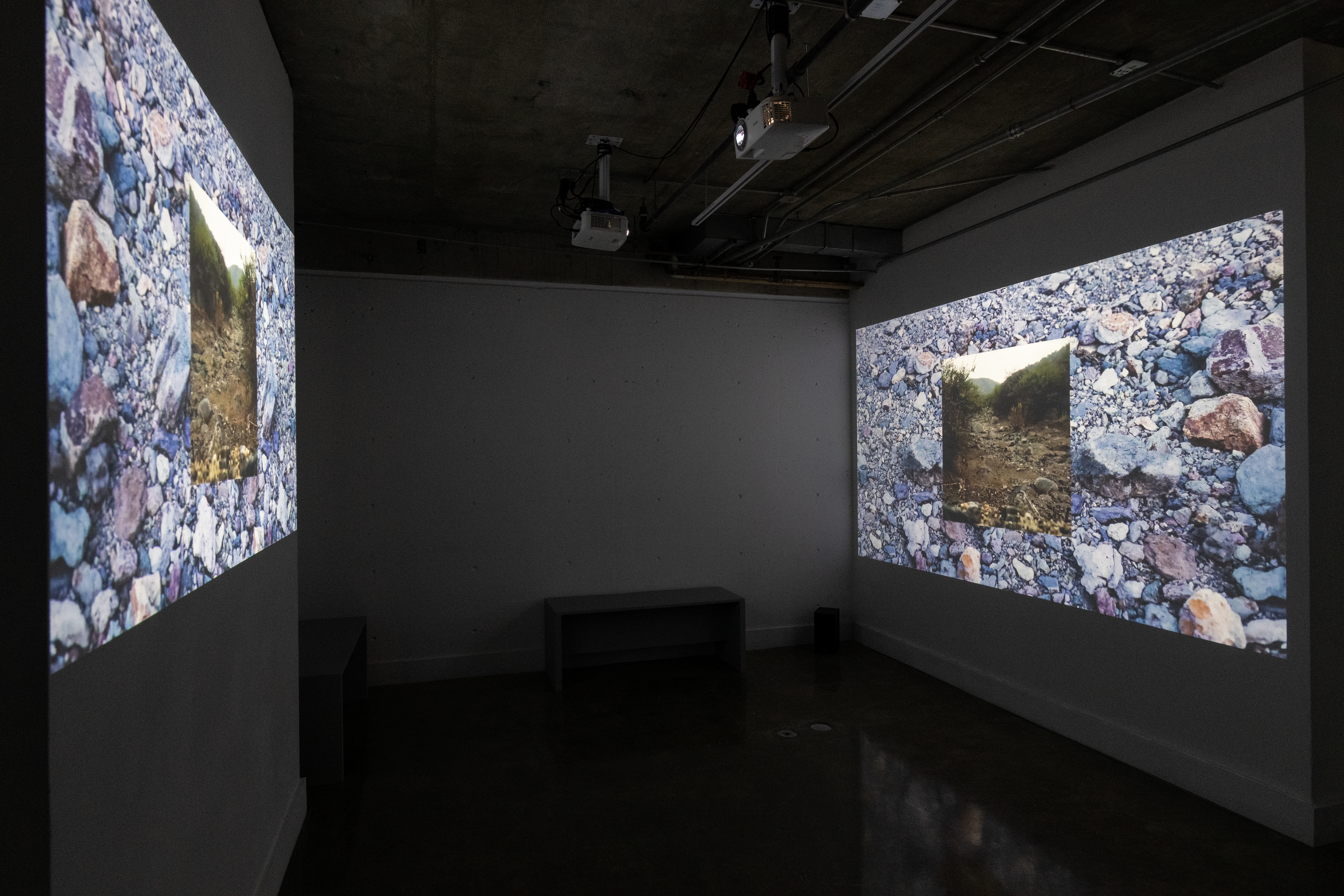 Two projections are shown simultaneously across from one another of rocks and a stream.