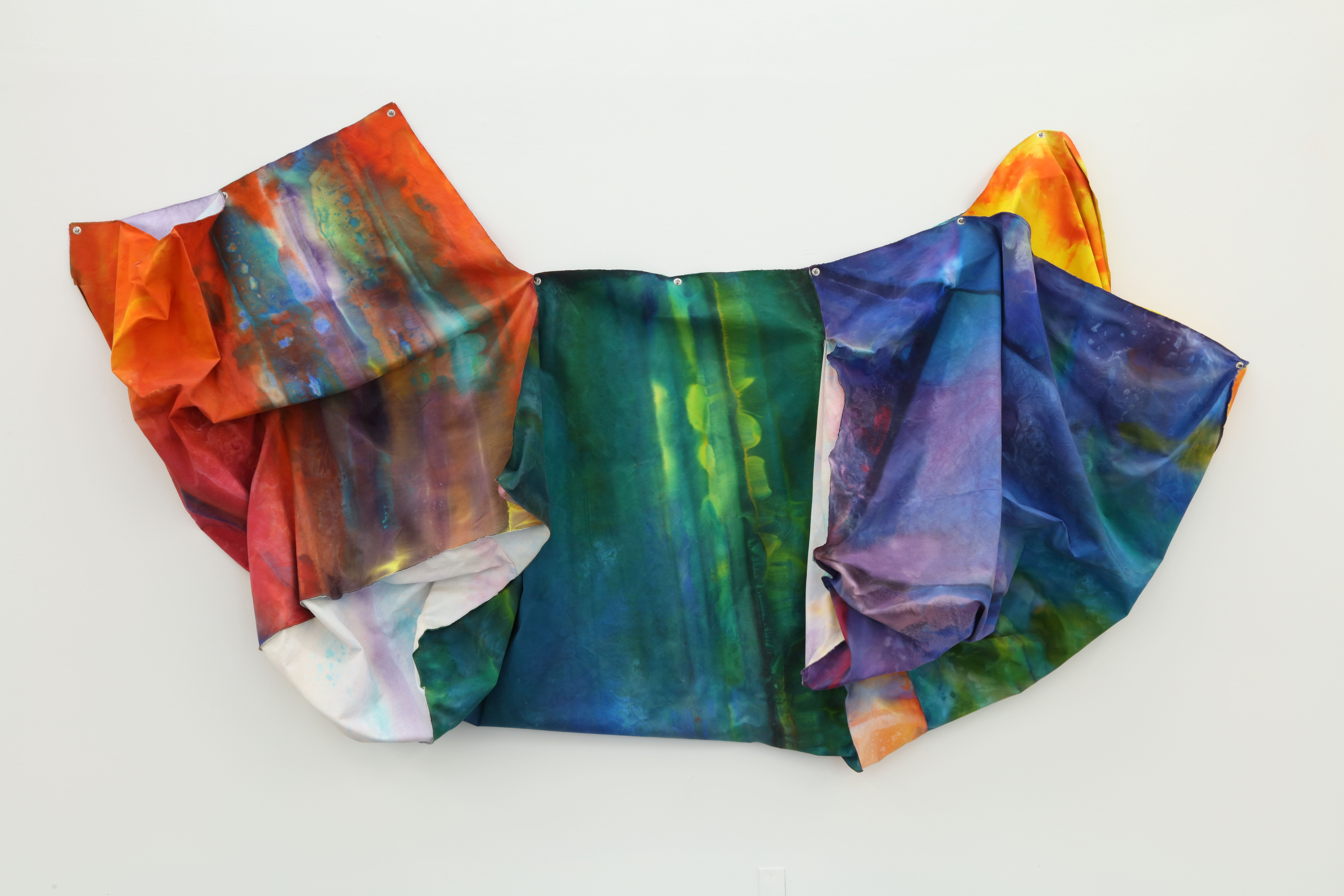 Colorful draped fabric on a blank wall.